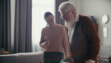 woman supporting elderly grandfather using walking at home