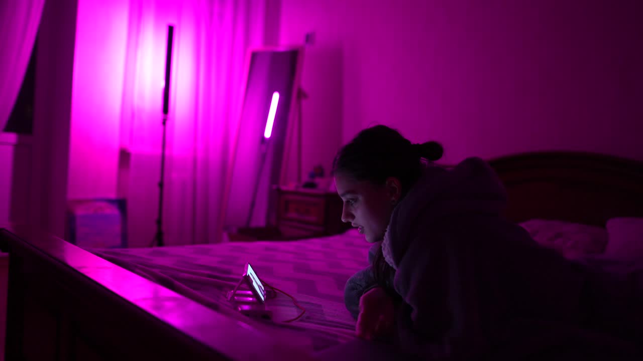 una adolescente en el dormitorio usando un teléfono inteligente