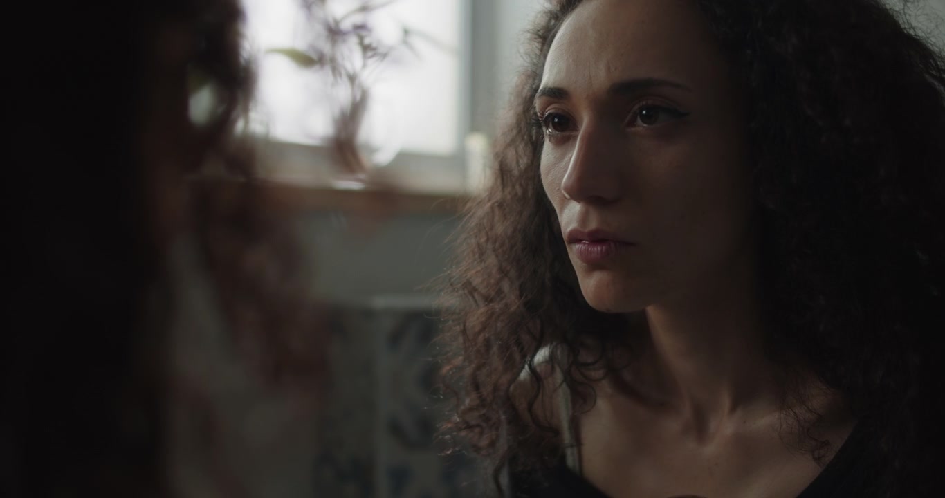 Girl sadly looking into the mirror