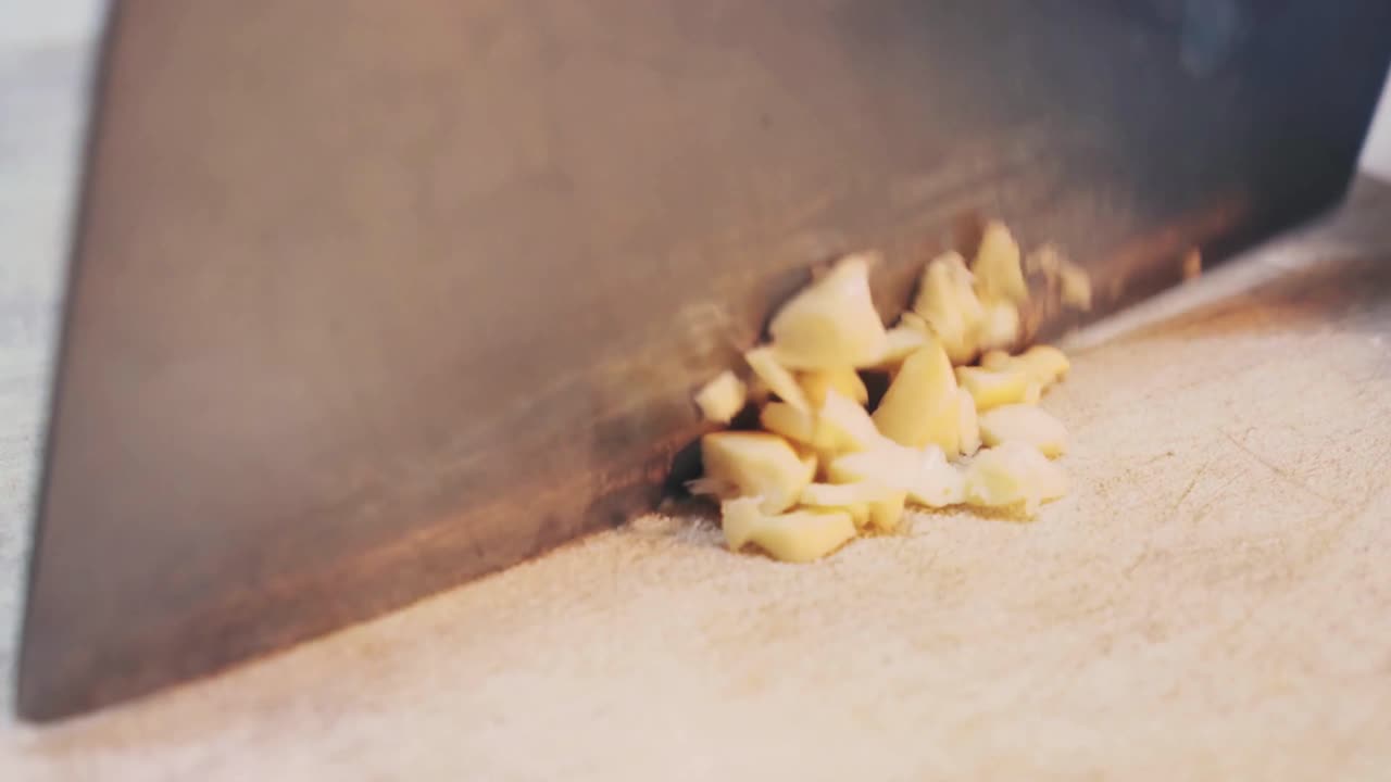 A chef slices garlic on chopping board close up