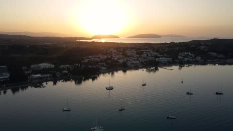 drone view of coastal mediterranean town with boats anchored with the sunrise in the background