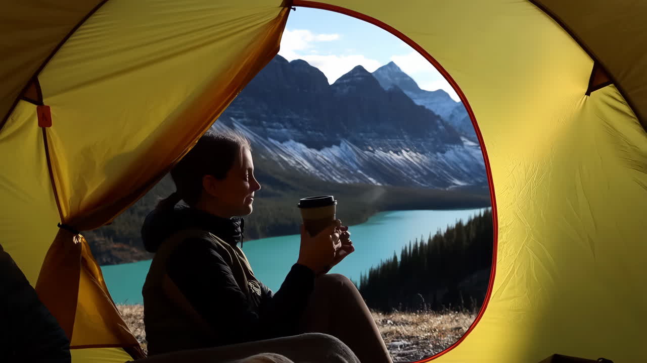 Woman enjoying a scenic mountain lake view from inside a tent