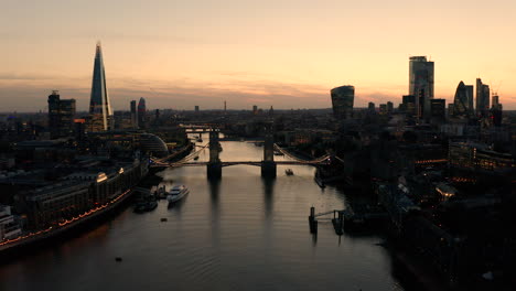 Aerial-view-of-London,-River-Thames-and-Tower-Bridge-just-after-the-sun-has-set-and-the-sky-is-lit