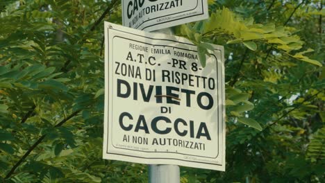 cartel que indica que la caza está prohibida en esta zona, el cartel está rodeado de naturaleza, rodeado de plantas y árboles verdes