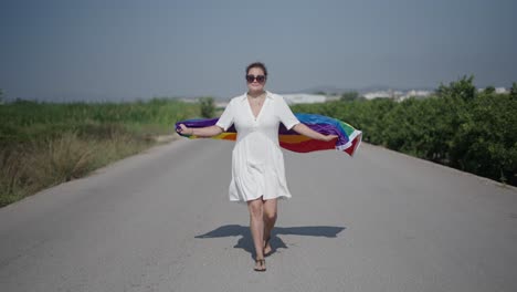 woman with rainbow flag walking down a road