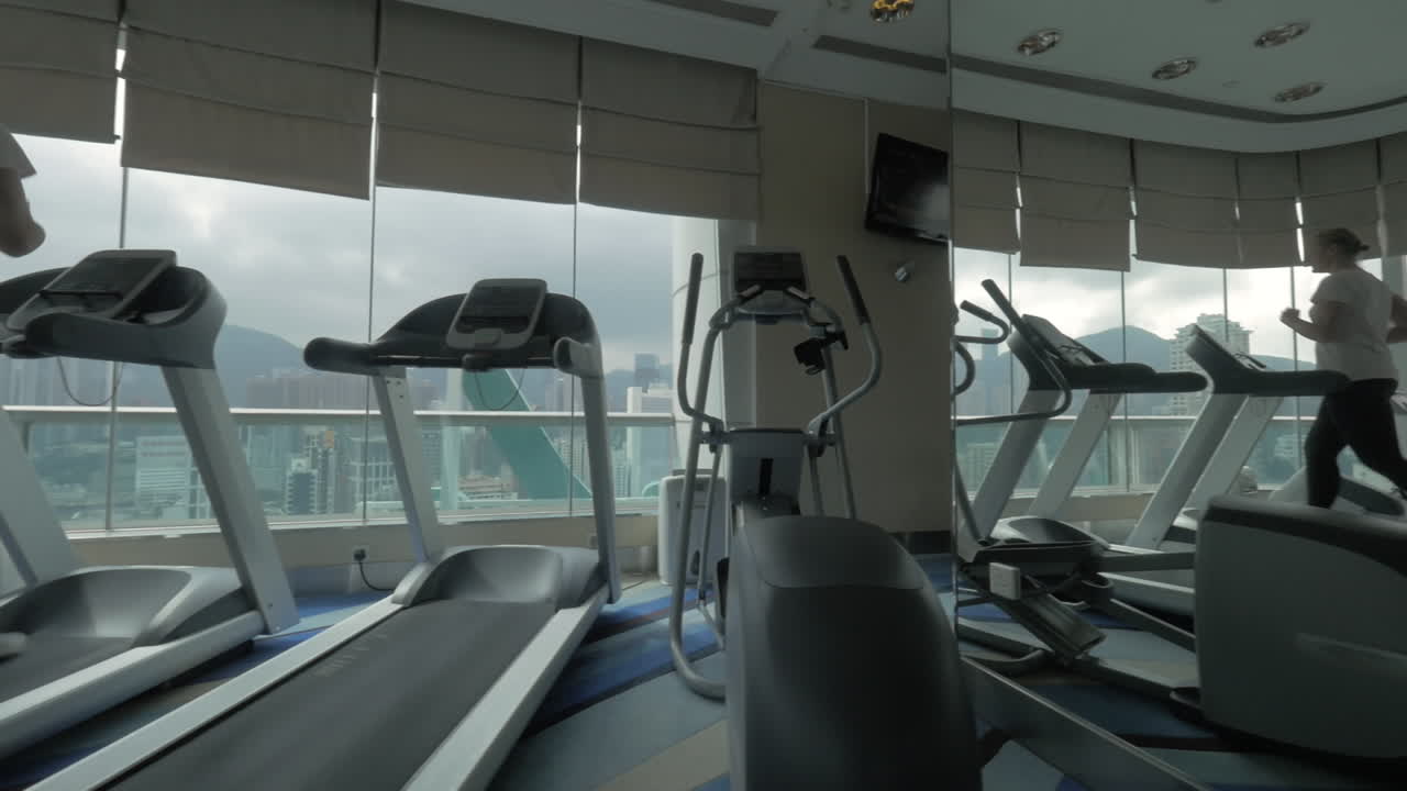 Woman exercising on running machine in front of panoramic window