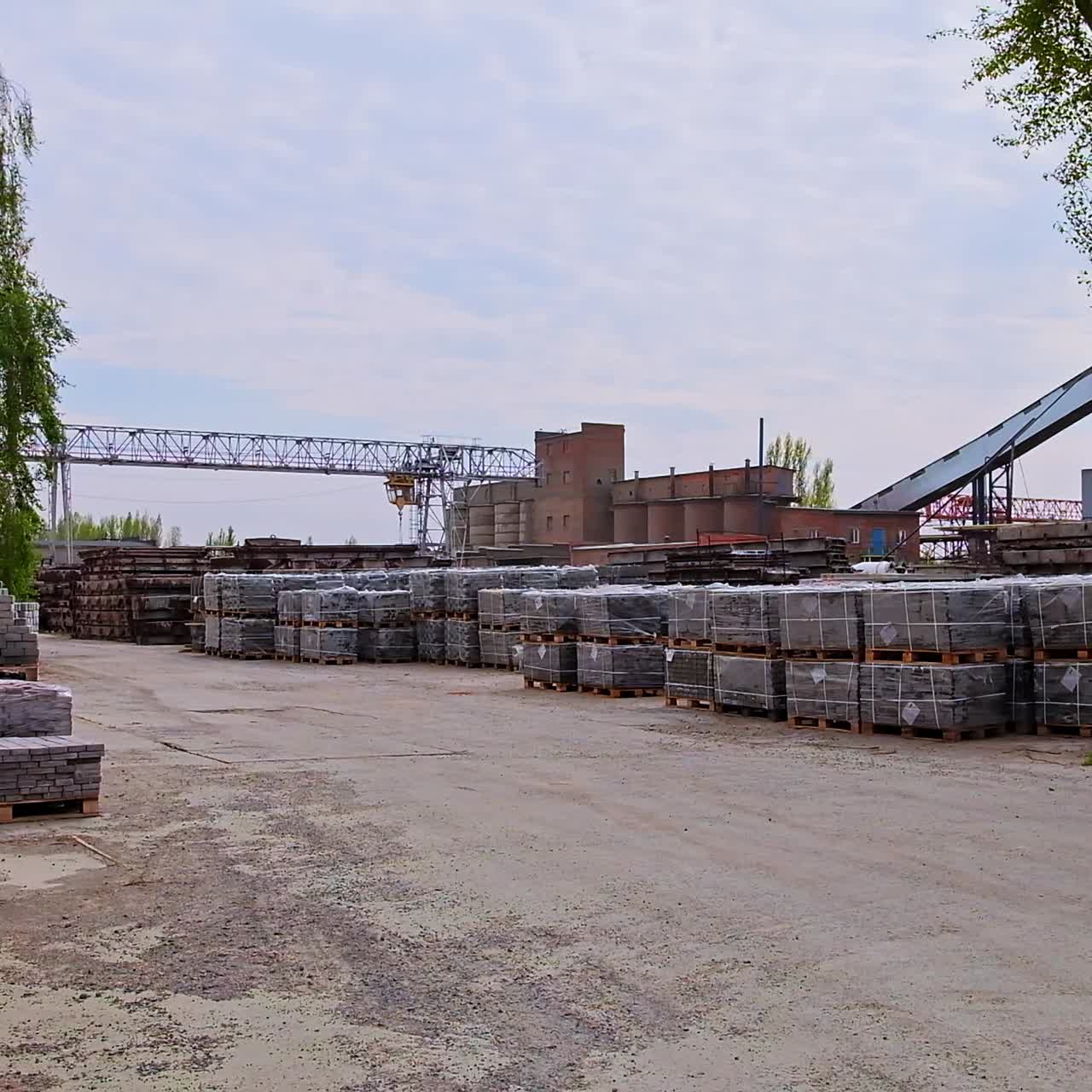Road leading to the construction site with building materials on both sides. Packs of new grey bricks covered with plastic