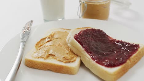 close up view of peanut butter and jelly sandwich in a plate with copy space on white surface