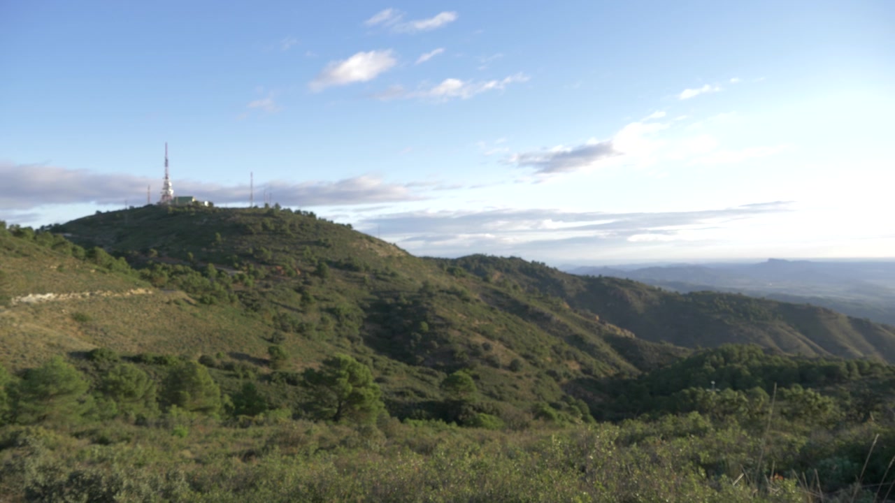 Panoramica a sinistra su una montagna con satelliti in cima e cielo azzurro sullo sfondo