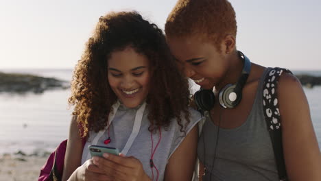 Dos-Amigos-Enviando-Mensajes-De-Texto-Navegando-Usando-El-Teléfono-Sonriendo-Felices-En-La-Playa-Soleada