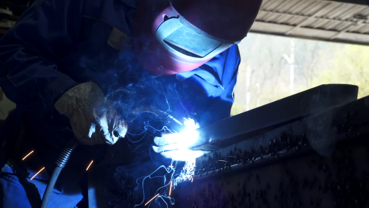 Anonymous workman welding metal construction in workshop