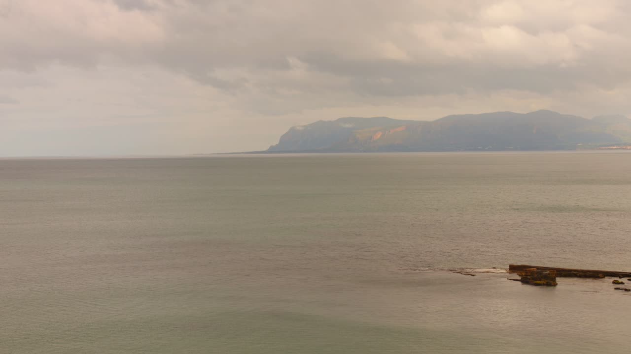 Calm seascape with a distant view of mountains on the coast of Sicily
