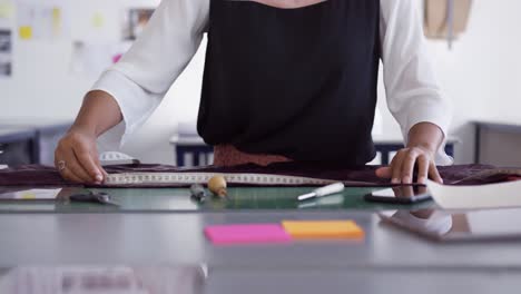 mujer de raza mixta tomando medidas en la oficina de moda
