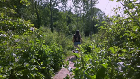 female wearing blouse and shorts walks with her dog surrounded by foliage