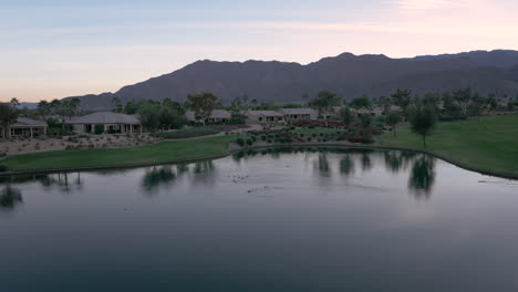 scenic residential golf course community with a tranquil lake and mountains at dusk