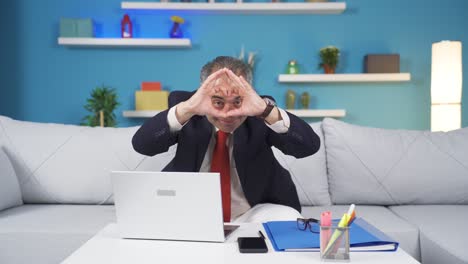 home office worker man makes heart symbol looking at camera.