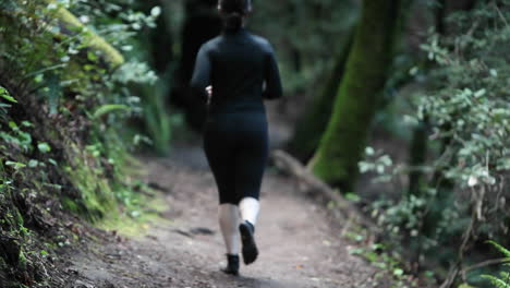 a woman jogs on a path in a wooded area