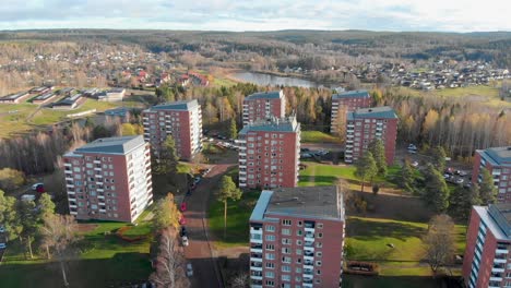 Imágenes-De-Drones-Sobrevolando-Una-Casa-De-Apartamentos-De-10-Pisos-En-Un-Pequeño-Pueblo-Con-Un-Lago-Y-Más-Casas-En-El-Fondo