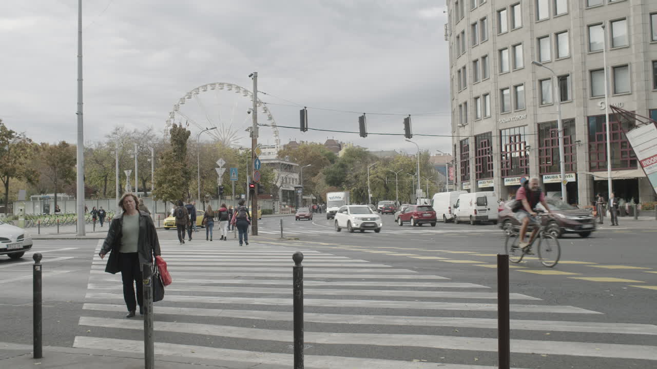 A young woman using her phone approaching a crosswalk, waiting to cross Bajcsy Zsilinszky road in the city of Budapest.