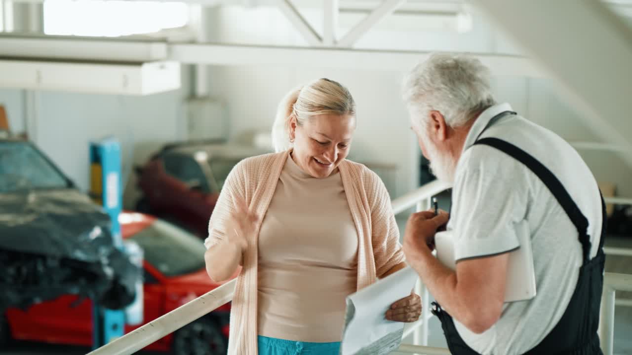 una agente de seguros adulta estrecha la mano con el mecánico en el servicio de automóviles.