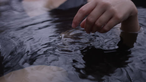 Female-hand-moves-through-water-in-outdoor-hot-tub