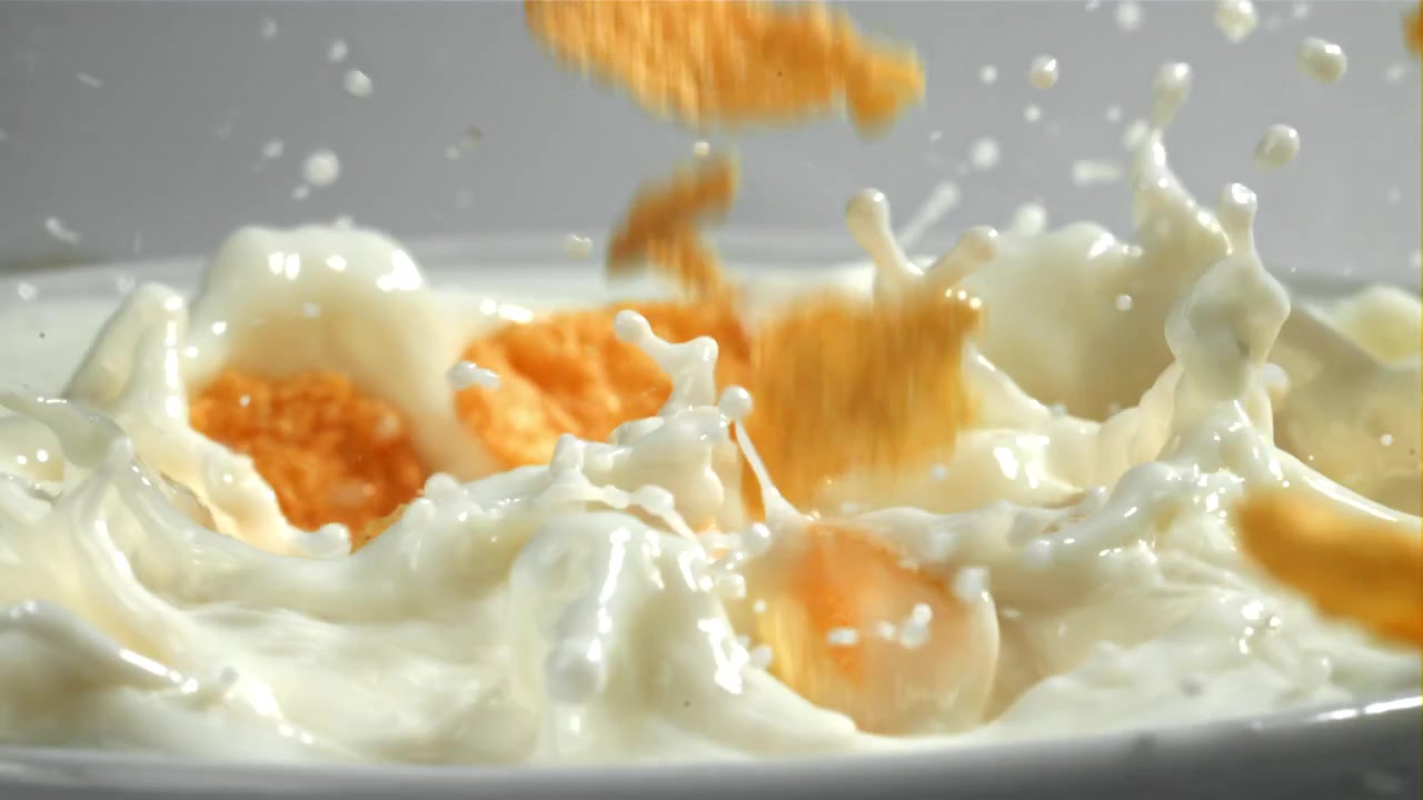 Cornflakes che cadono al rallentatore nel latte con schizzi