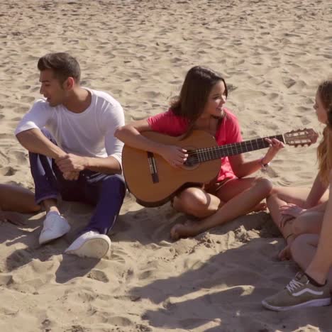 young woman playing guitar to her friends