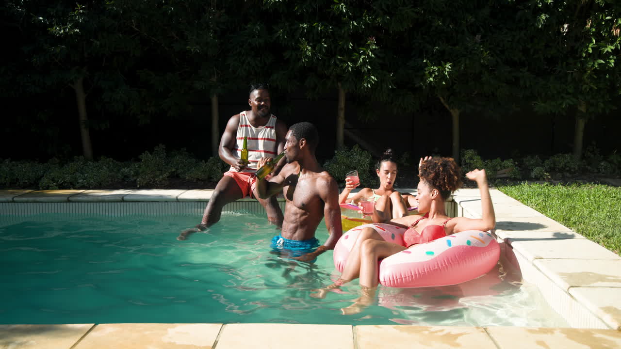Vielfältige Freunde genießen eine Poolparty, lachen und entspannen auf einer aufblasbaren Schwimminsel mit Getränken.