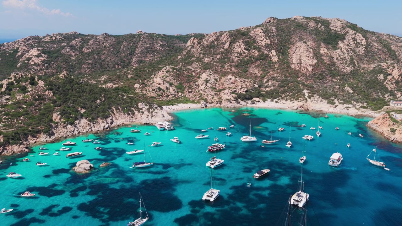 Large vue aérienne de yachts à voile de luxe dans une eau bleu turquoise, avec une magnifique plage de sable nichée dans des falaises de granit sur l'île de Spargi dans l'archipel de la Maddalena en Sardaigne, Italie.