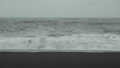 waves crash on a black sand beach in iceland