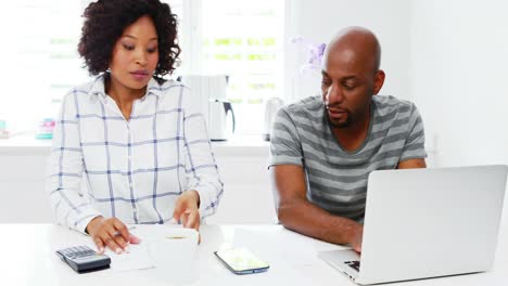 Man-using-laptop-while-woman-calculating-bills-4k