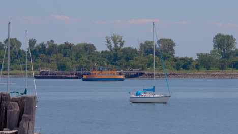 Roll-on,-roll-off-orange-ferry-heading-to-Hart-Island,-boats-and-dock-in-the-foreground