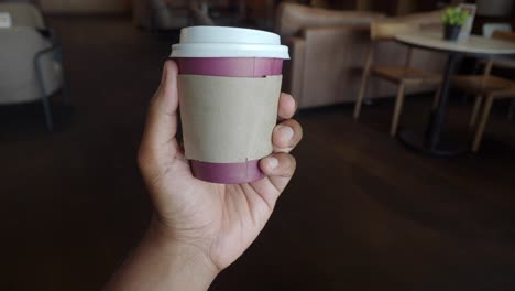 una persona sosteniendo una taza de papel rojo de café