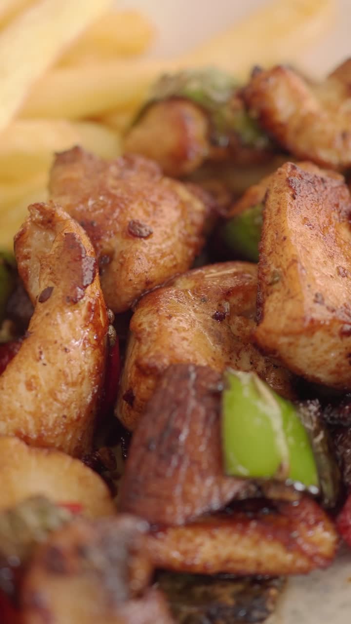 Deliziosi pezzi di pollo cotti con peperoni e patatine fritte dorate