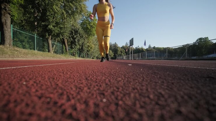 Donna che corre su pista all'aperto in abbigliamento sportivo giallo