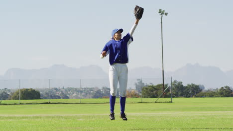 caucasian female baseball player, fielder jumping and catching ball on baseball field