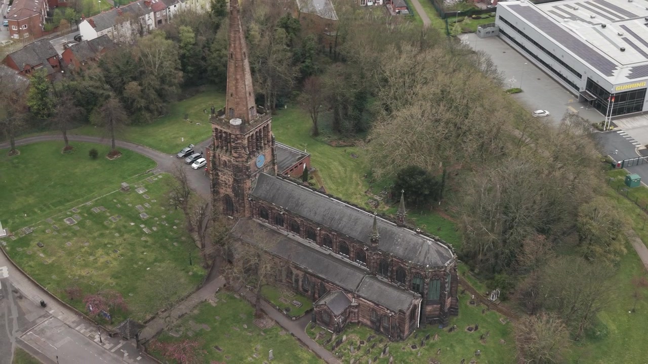 Aerial view of Aston Parish Church in Birmingham, United Kingdom, with its tall spire beside roads and trees.