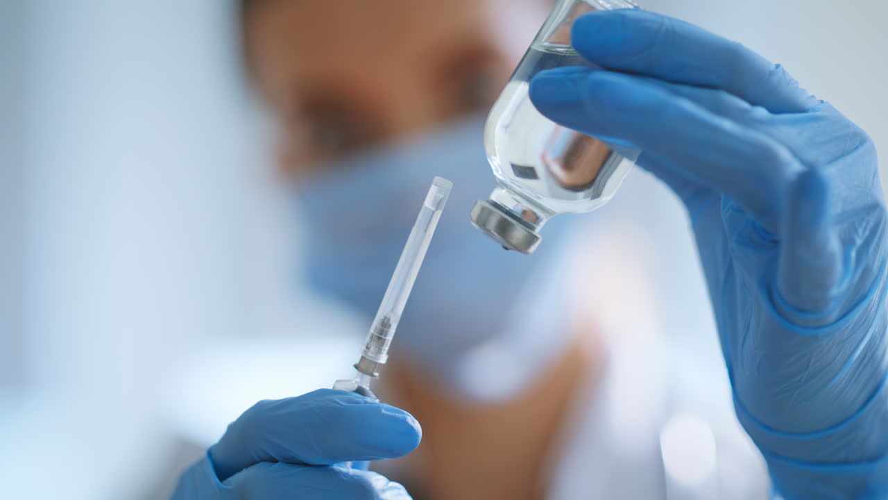 Physician hands filling syringe medication closeup. Doctor preparing vaccine