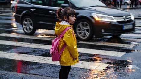 little girl crossing the street in the rain