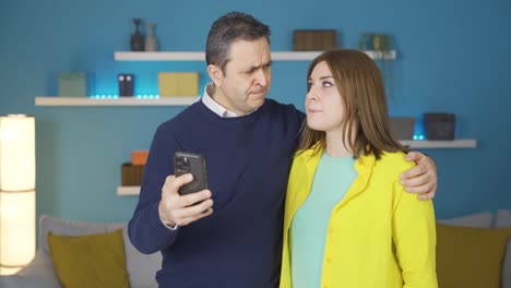 Father-and-young-daughter,-upset-by-what-they-saw-on-the-phone.
