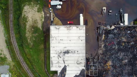 aerial top view over a burnt industrial business, extinguished fire of hazardous materials, oil pollution