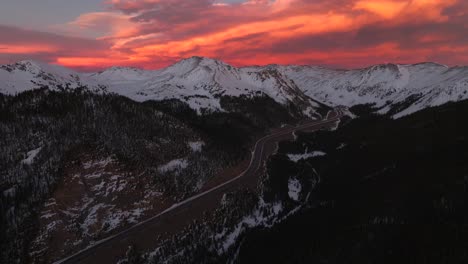 rocky mountains aerial drone i70 highway winter solstice colorado vibrant orange red cloudy skies setting sunset cars trucks traffic coon hill parshall eisenhower tunnel continental divide forward pan