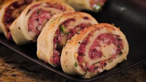 homemade pepperoni roll italian stromboli sliced and displayed in a black plate, slider motion close up