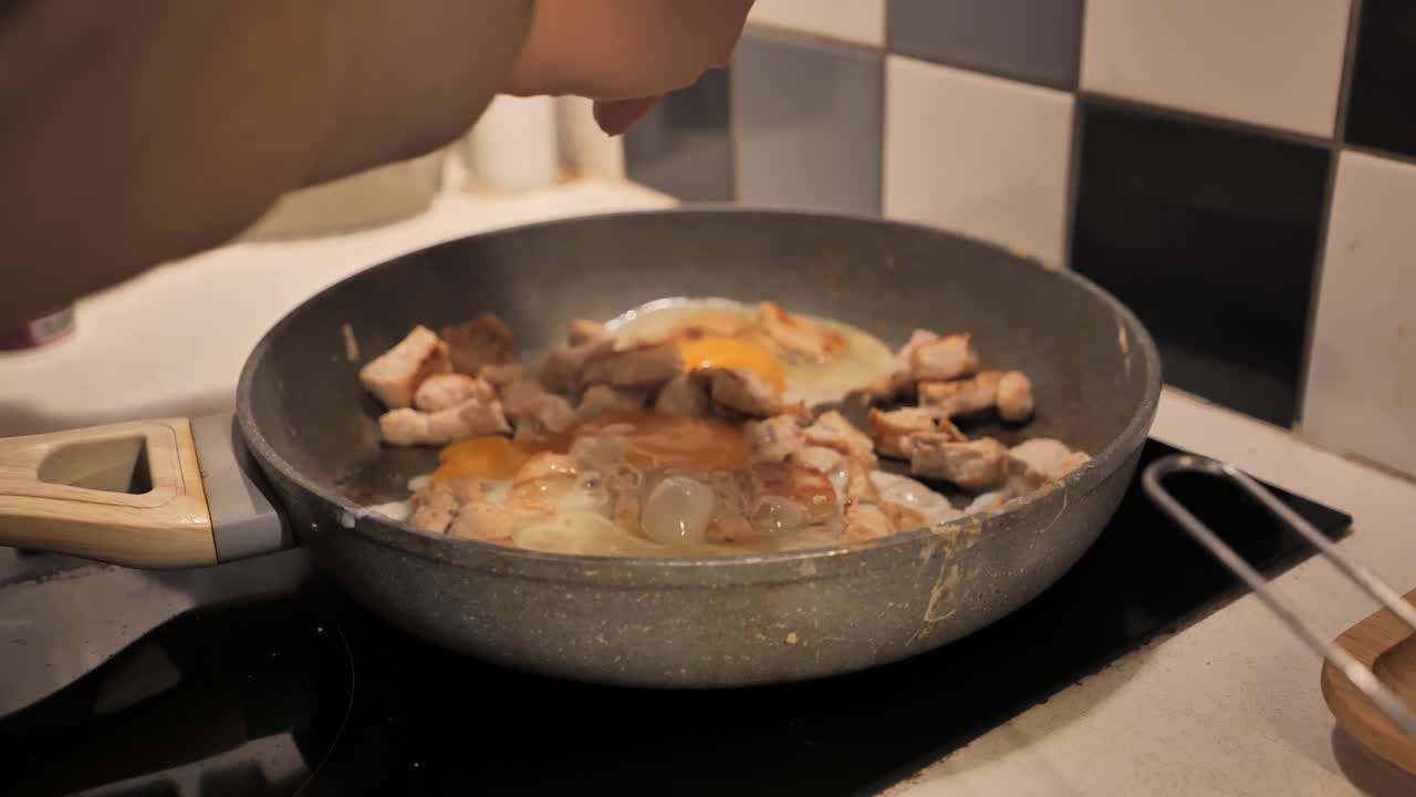 Cooking eggs and meat in a frying pan