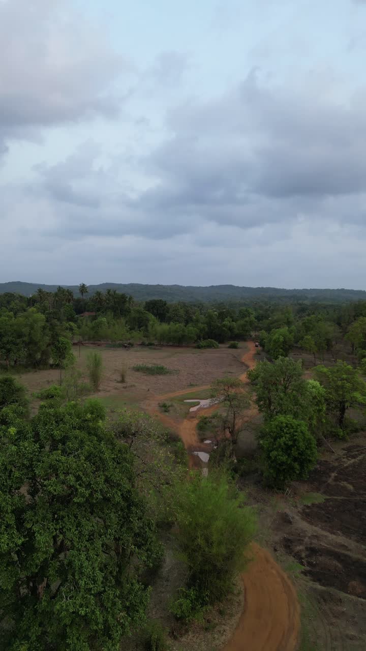 A mesmerizing 4K forward moving drone view of Avalegaon village in Konkan, Maharashtra, India, showcasing its charm with lush green trees, vast fields and mountains under a cloudy sky