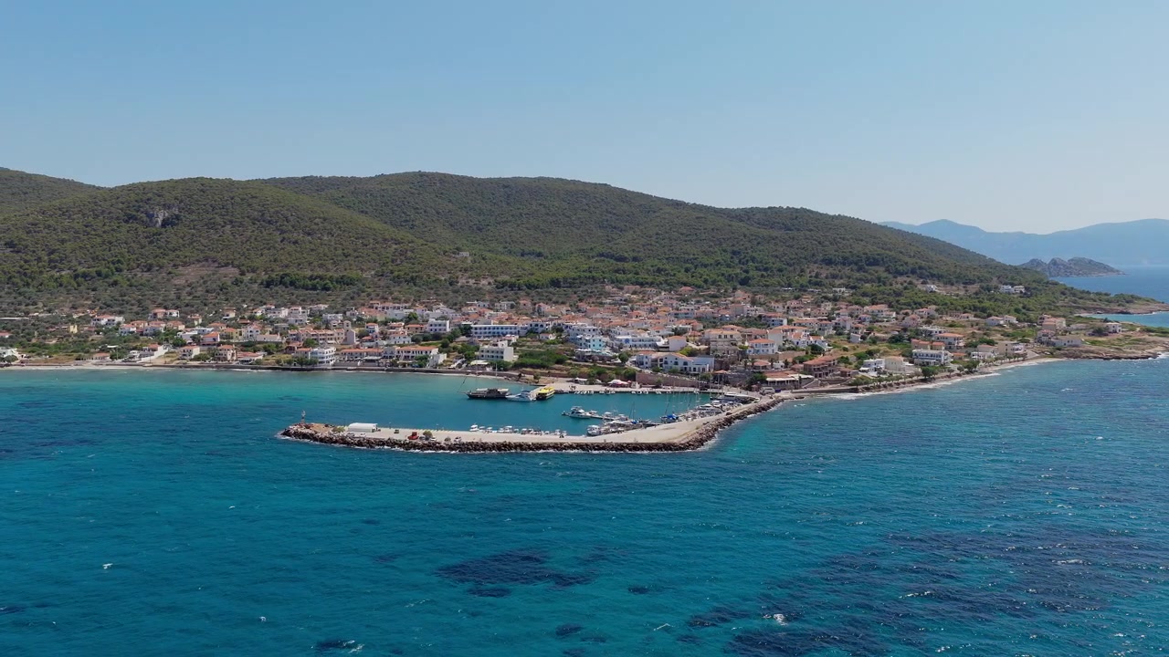 Yunanistan, Agistri adasındaki Megalochori köyü ve limanının panoramik drone çekimi. Kristal berraklığında su, güneşli yaz günü, bulutsuz gökyüzü