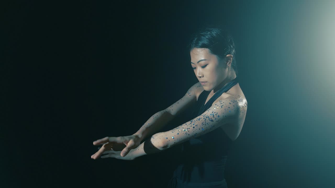 Jovem mulher japonesa encantadora dançando balé na névoa com fundo preto.
