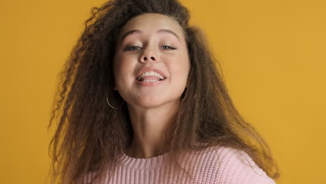 caucasian curly haired woman smiling to the camera.