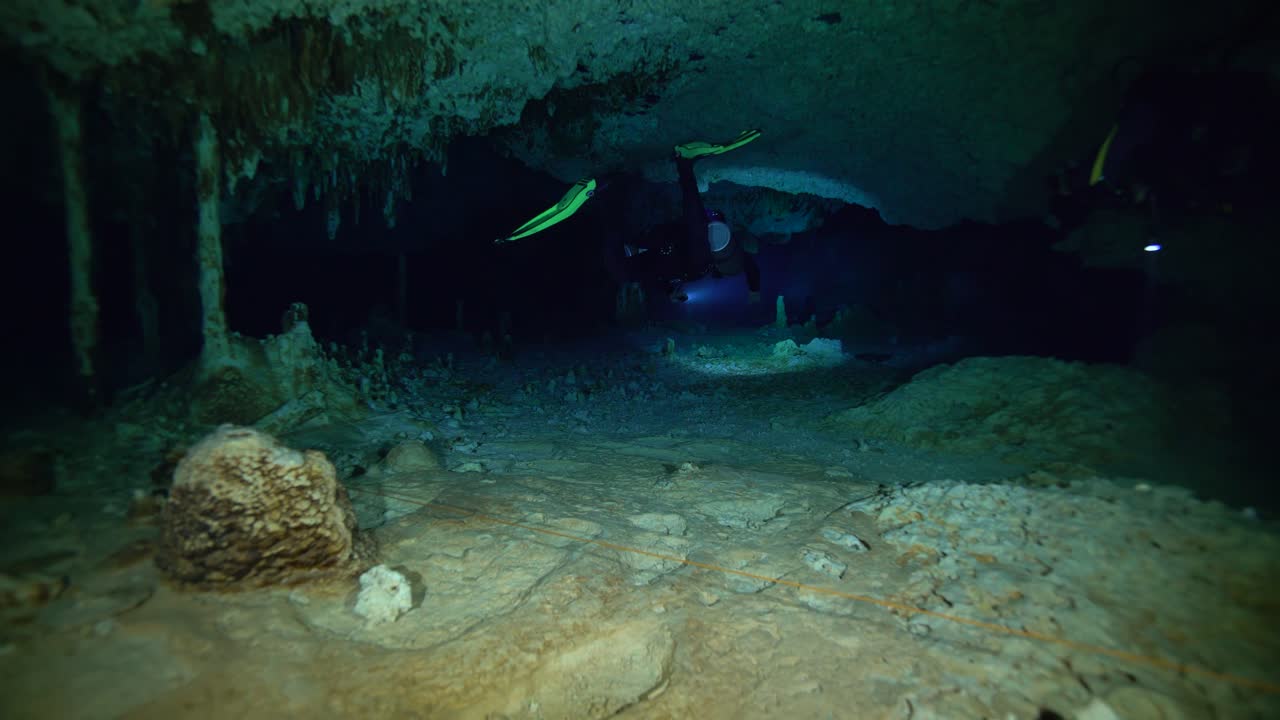 los buzos nadan a través de un estrecho túnel frente a la costa de la península de yucatán en méxico.