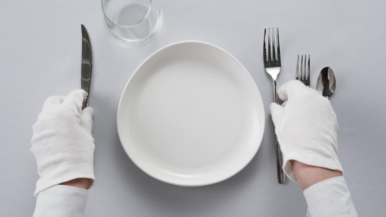 Elegant table setting with white tableware plates, cutlery, and glassware for a classy dining, fancy expensive restaurant dinner